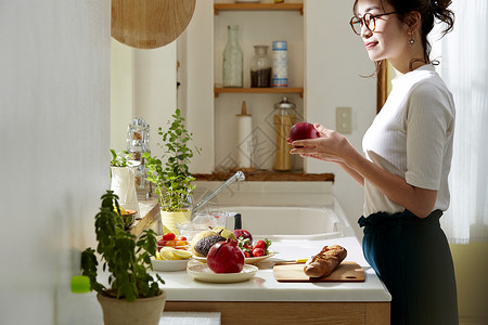 在窗边料理台制作午饭的女人背景图片