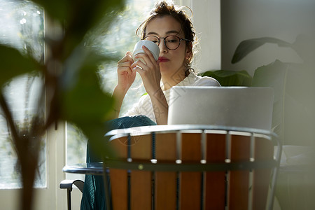 女人坐在窗边的桌上喝咖啡工作玻璃高清图片素材