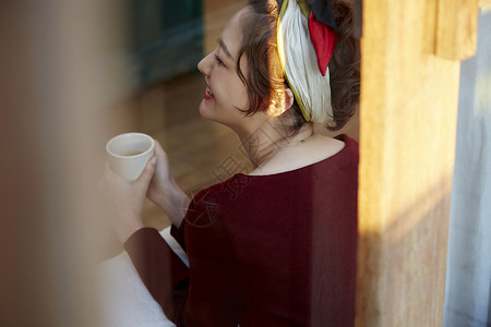 女人坐在窗边的木地板上看书喝咖啡图片