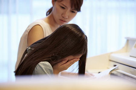 搜藏失败老师看着钢琴前哭泣的女孩背景