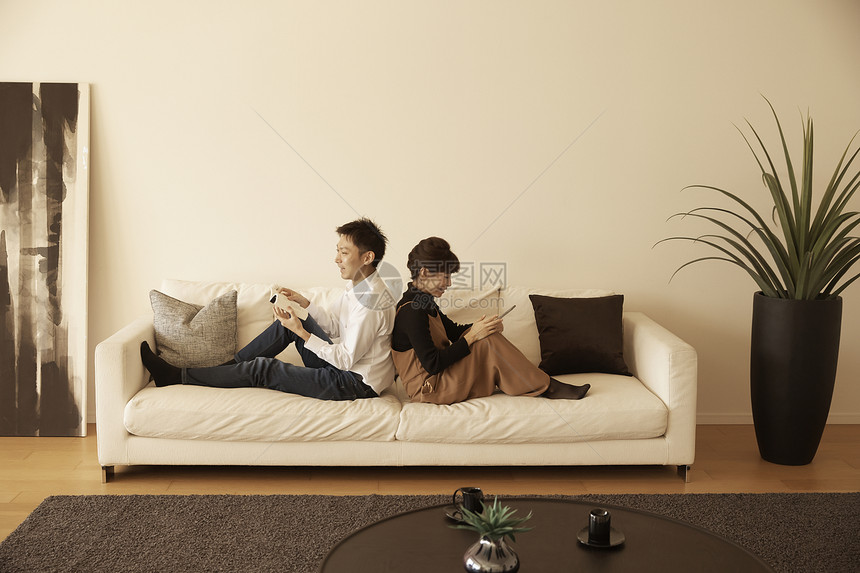在公寓沙发上坐在一起放松说笑的情侣图片