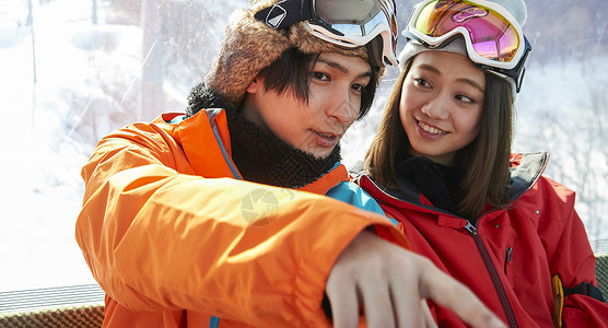 乘坐滑雪缆车上雪山的男女青年图片