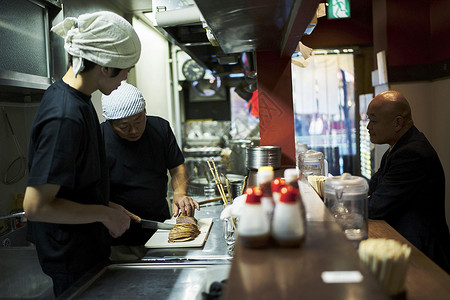 在制作食物的厨师和等待用餐的顾客饭店高清图片素材