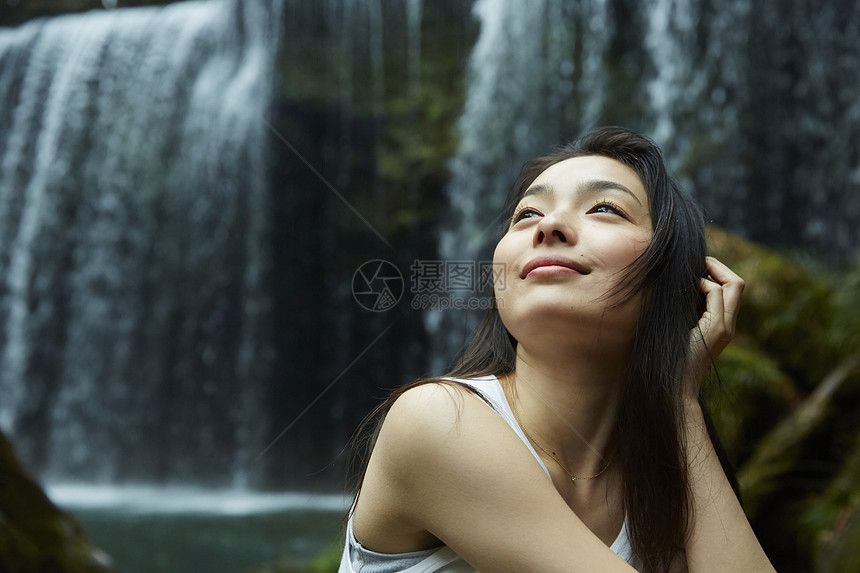 站在小溪边享受瀑布的女人抬头看图片