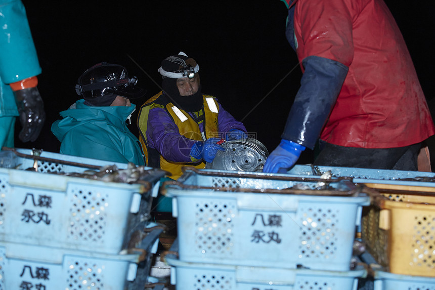 夜晚收获的渔业渔民在搬运卸货图片