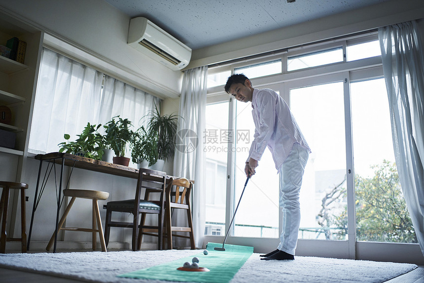 在客厅里打高尔夫球的男士图片
