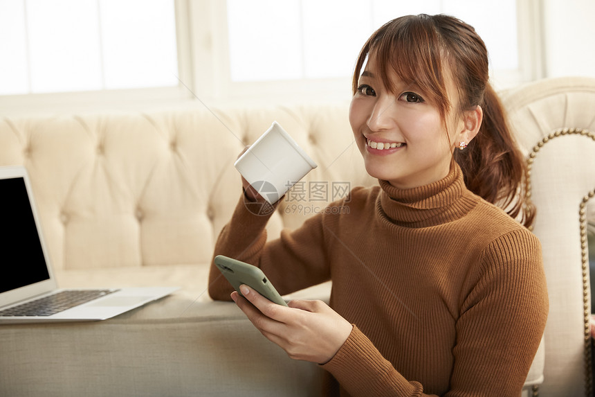 居家坐在电脑面前拿着手机的女孩图片