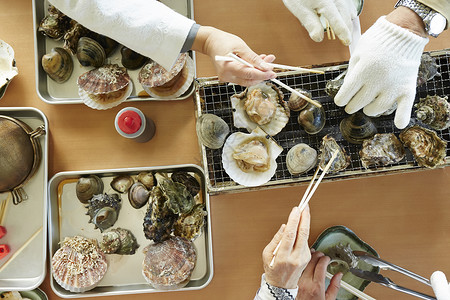 游客吃海鲜烤贝类特写高清图片