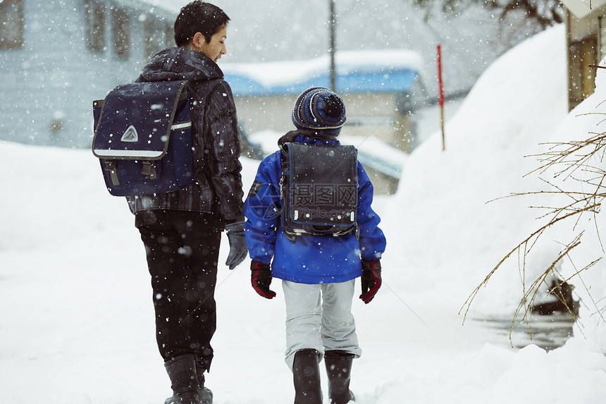 下雨天背着书包雪地里行走的学生图片
