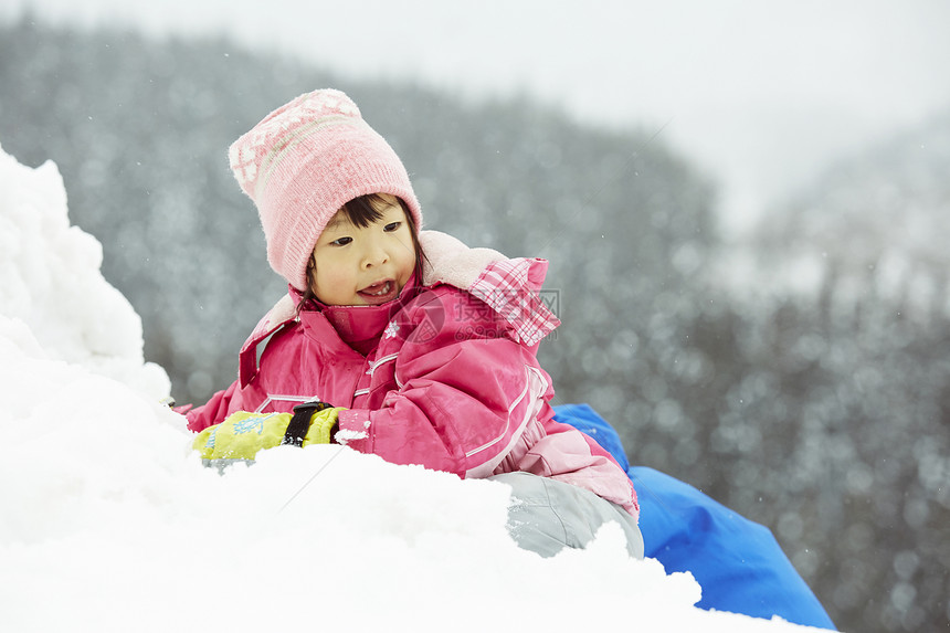 趴在积雪上玩耍的小女孩图片