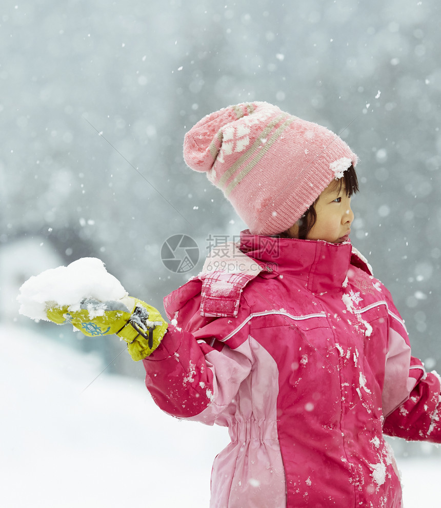 雪地里拿着雪球投掷的小女孩图片