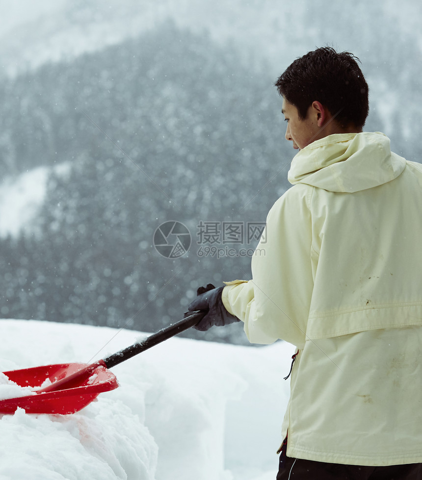 使用雪铲铲雪的男孩图片