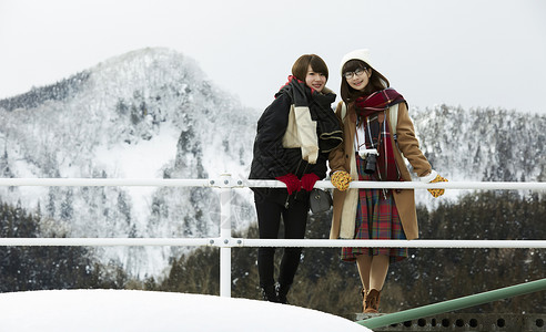 冬天女孩在旅途雪景驻地看前方好朋友高清图片素材