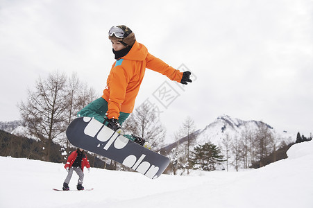 计谋滑雪场跳起抓板的男青年背景