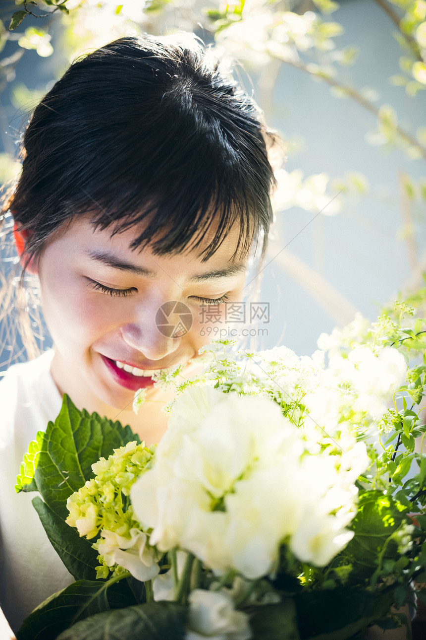  阳光下抱着花的女性图片