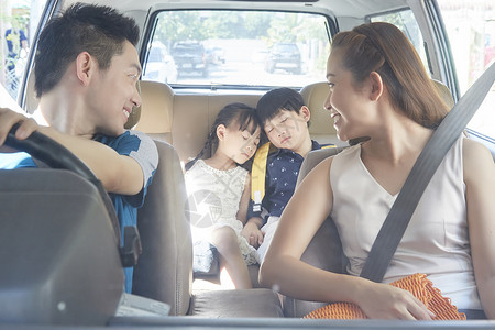 车中的父母回头看向在车后座上睡着的儿女图片