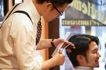 正在给客人剪头发的理发师剪刀高清图片素材