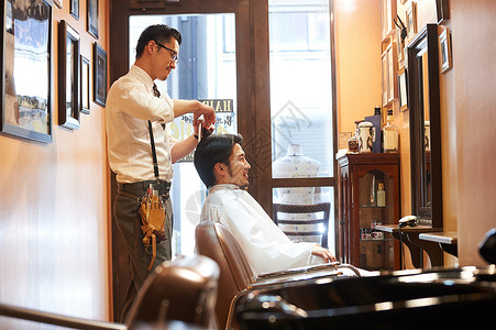 正在给客人剪头发的理发师商业高清图片素材