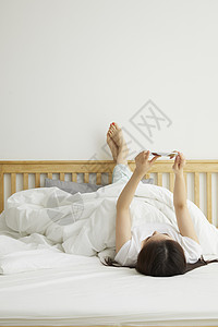 躺在床上玩手机的居家女性日常生活图片