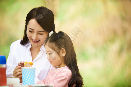 食物和女孩公园里郊游玩耍的女儿和母亲背景