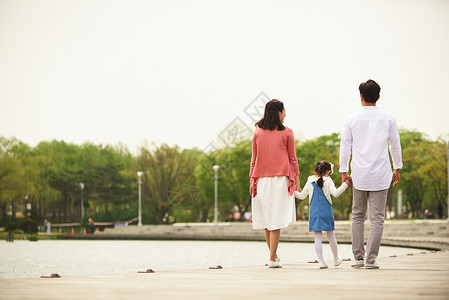 河岸边散步的一家人背影图片