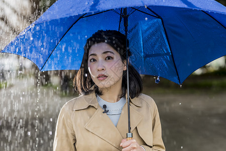 撑着蓝色雨伞的年轻女性下雨天图片