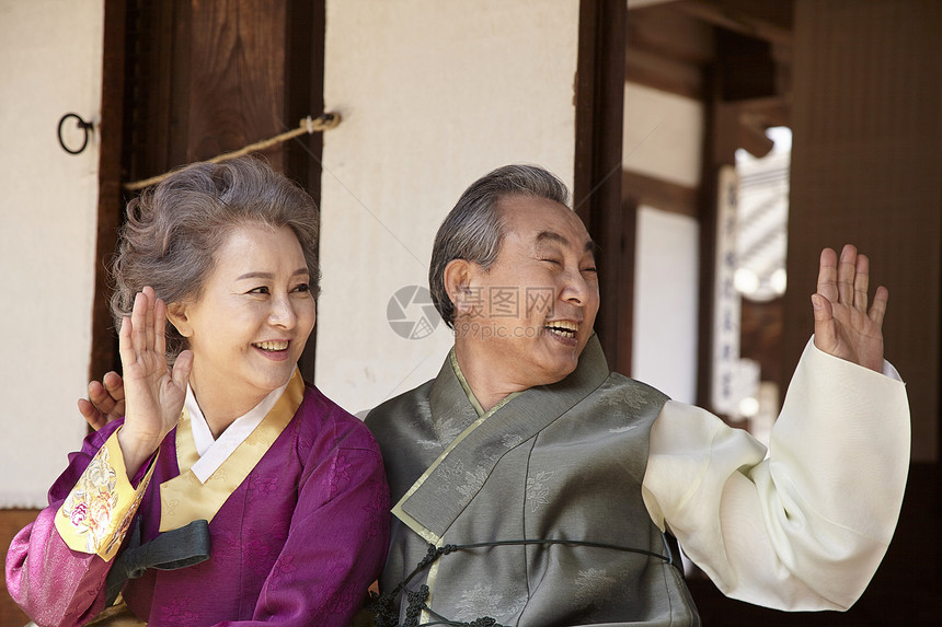 穿着传统服装坐在屋外开心的打招呼的夫妇图片