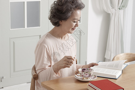 喝着茶看书阅读的老年女性图片