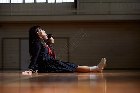 即将毕业的女学生坐在体育馆地板上发呆图片