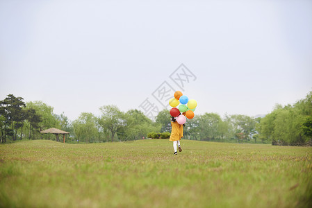 户外草坪拿着气球奔跑的小女孩背影图片