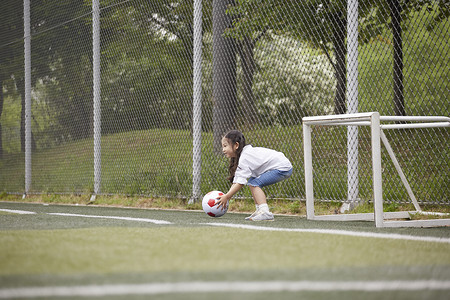 运动场拿着足球的小女孩背景图片