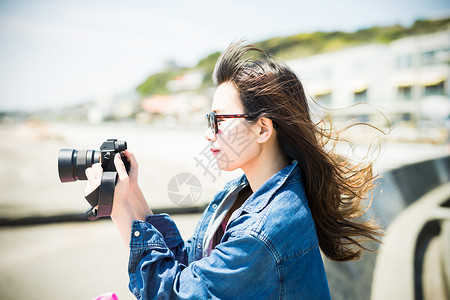 夏日女孩在海边用相机拍照图片