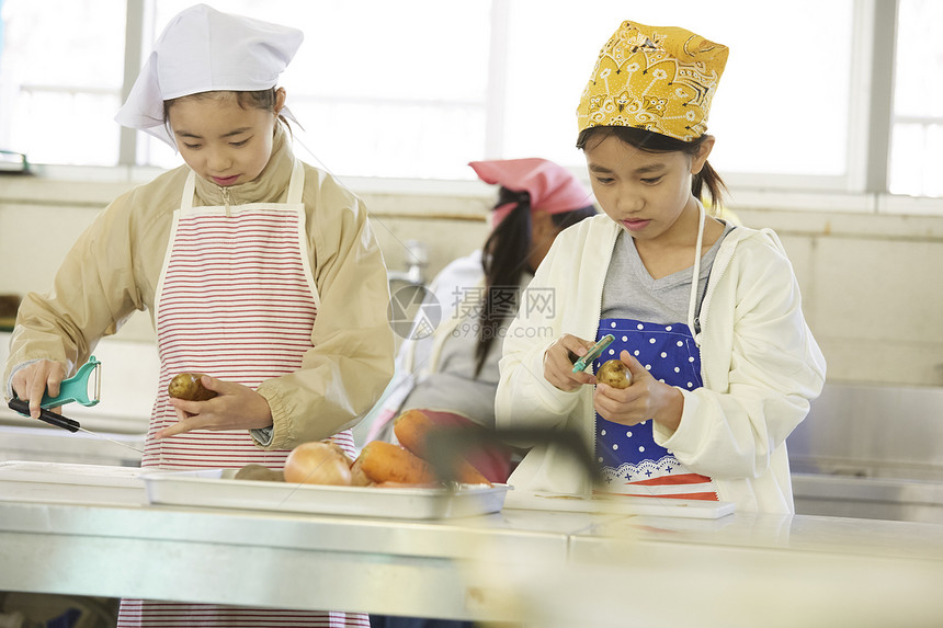 厨房里穿着围裙戴着头巾料理食材的女孩们图片