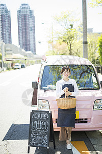 靠在餐车前拿着篮子微笑的年轻女性图片素材