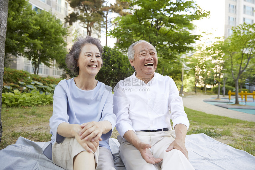 坐在楼下公园草坪上的老年夫妇图片