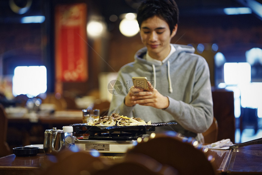 餐馆里拿着手机的男性图片