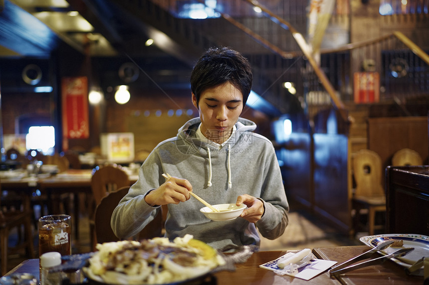 餐厅里吃着烤肉的男青年图片