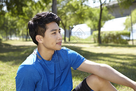 坐在公园草坪上休息的男青年背景图片