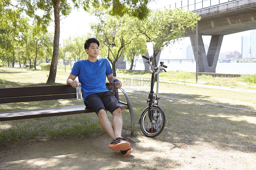 坐在长凳上休息的男青年图片