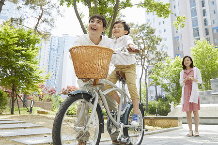年轻父母陪着儿子骑自行车爸爸高清图片素材