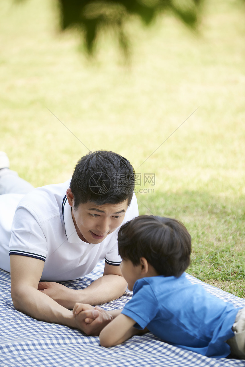 趴在野餐垫上的父子图片