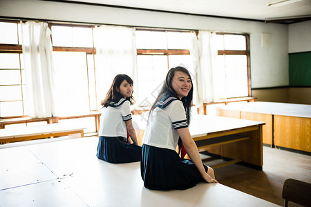 坐在桌子上穿着学校制服的女高中生早晨高清图片素材