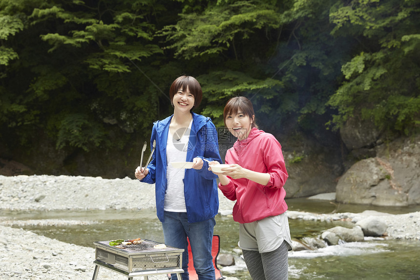 两个女人在河岸边放松享受户外烧烤