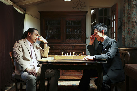 穿着西装下国际象棋的成熟男性图片