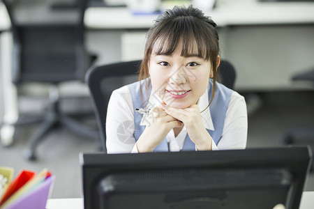 坐在工位上微笑的职业女性图片