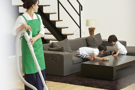 家政女保洁使用吸尘器打扫卫生孩子气的高清图片素材