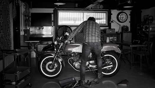 在车库修理摩托车的男性图片