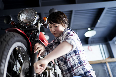 修理摩托车的妇女图片