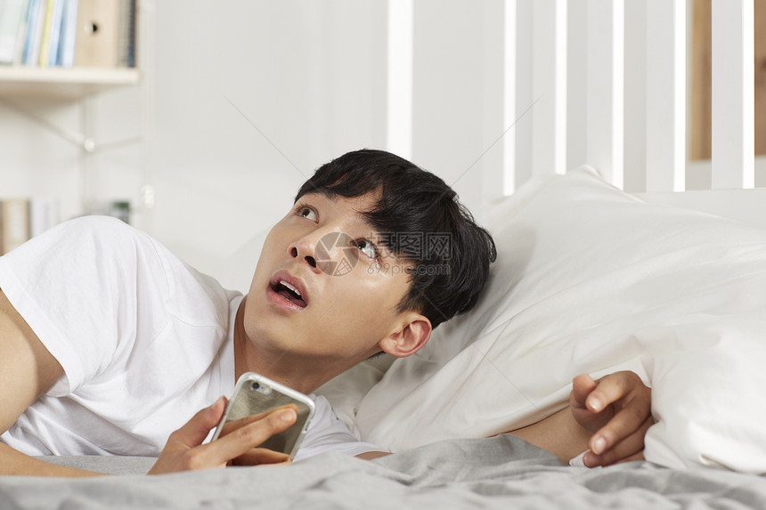 青少年躺在床上玩手机图片