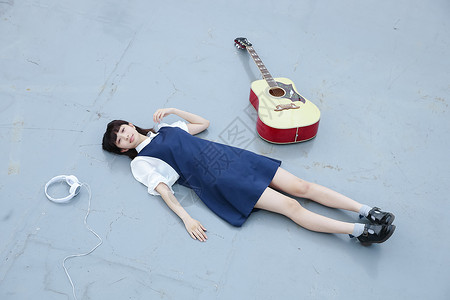 躺在地上的女孩和她的吉他房顶高清图片素材